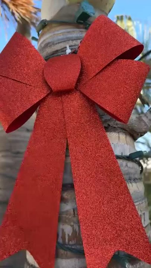 A holiday bow finishes a wrapped palm trunk