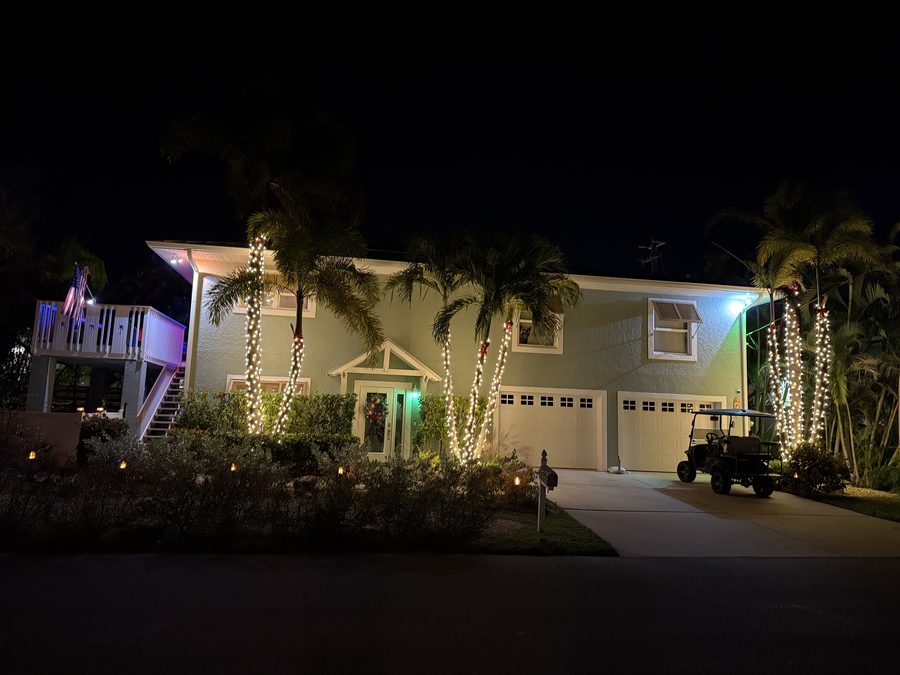 Coastal home with illuminated palms and a lit deck