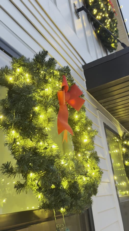 Close-up of an illuminated wreath with a red bow on a window