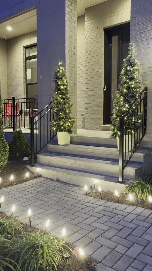 Modern entryway with lit topiary trees and pathway lighting stakes