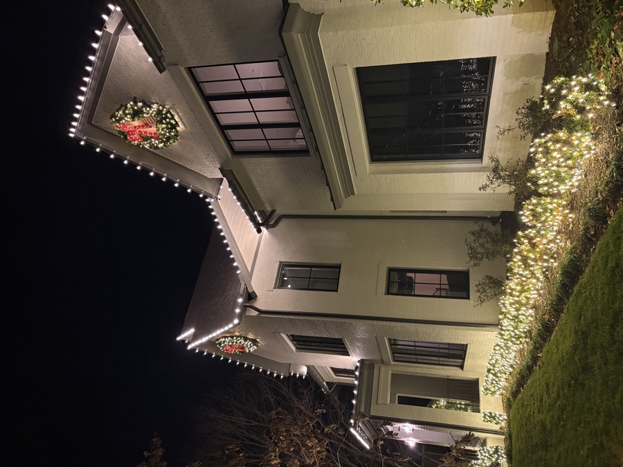 Close angle of a stucco estate with wreaths and landscape bed lighting