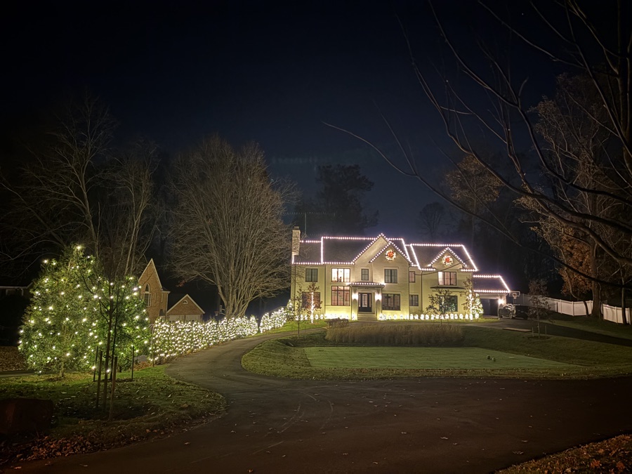 Home with a circular driveway and a large lit conifer tree