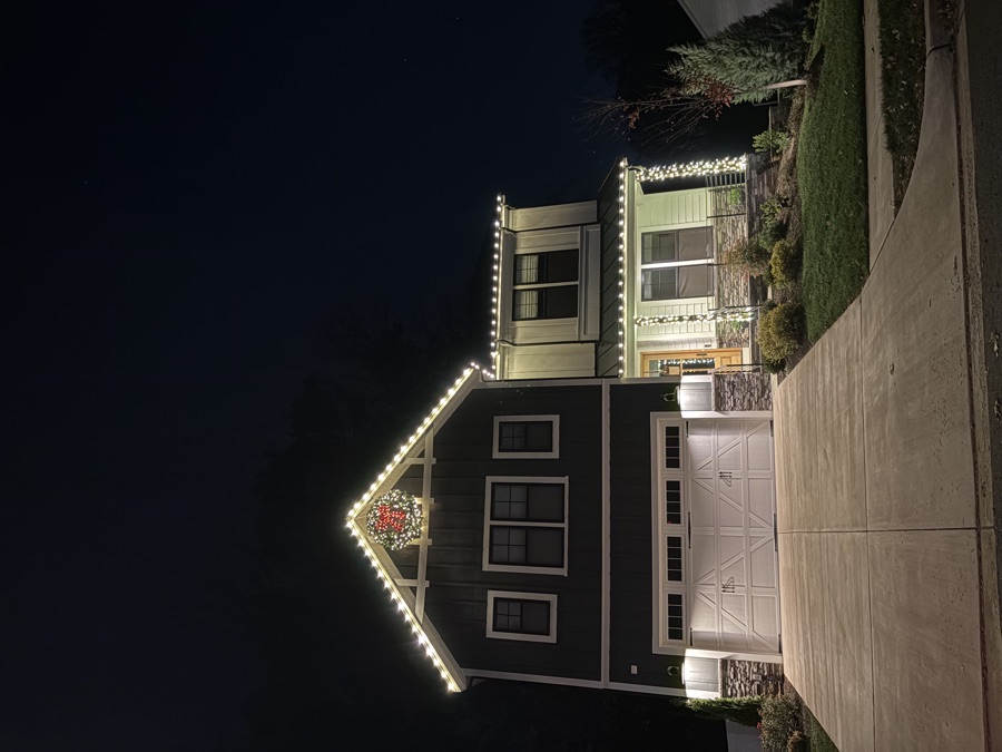 Craftsman-style home with roofline lighting and a wreath over the garage