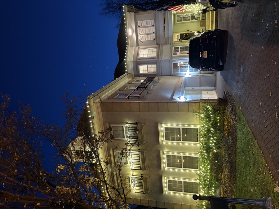 Elegant stucco estate with roofline and column lighting at dusk
