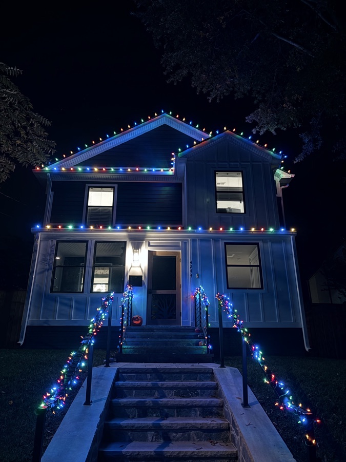 Historic-style home with multicolor roofline lighting and railing garland
