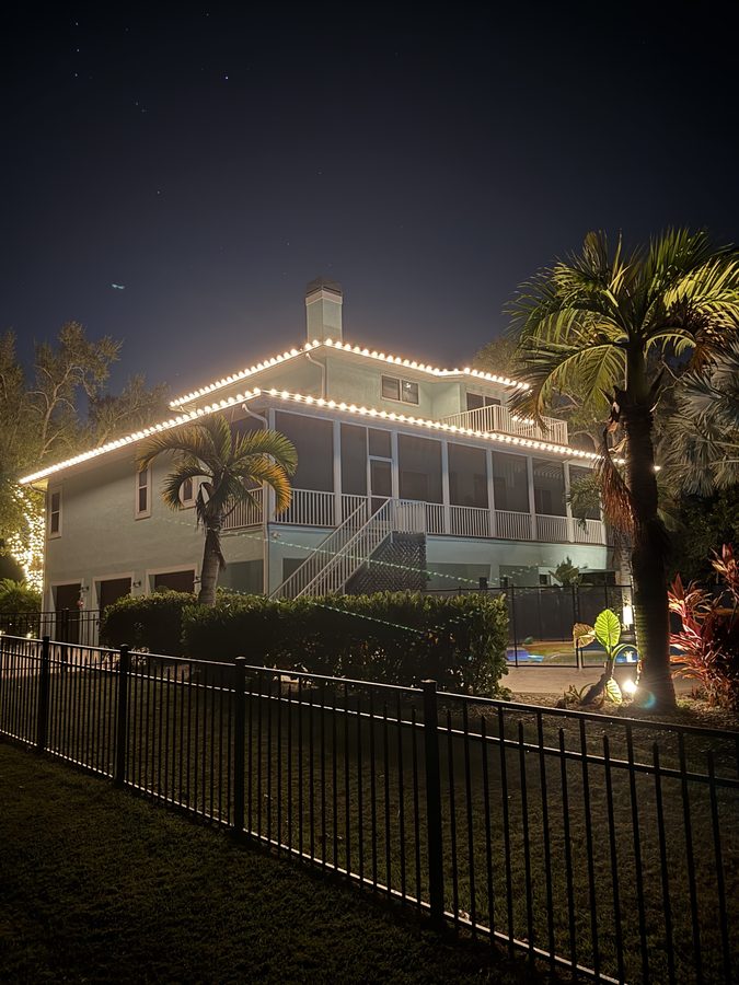 Screened waterfront lanai with roofline lighting and a lit palm
