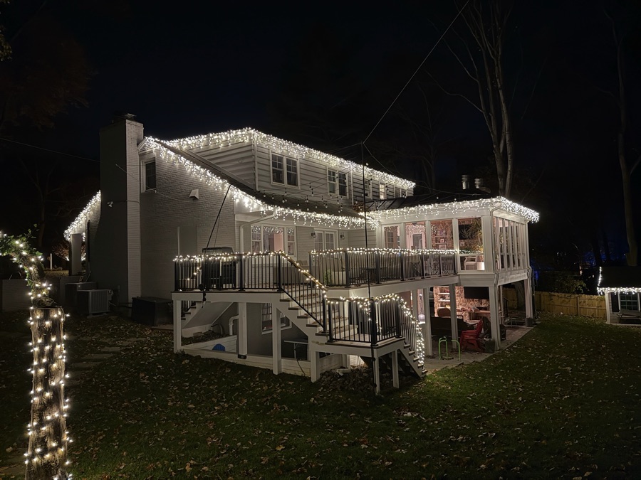 Rear view of a home with a multi-level deck, roofline, and railing lighting