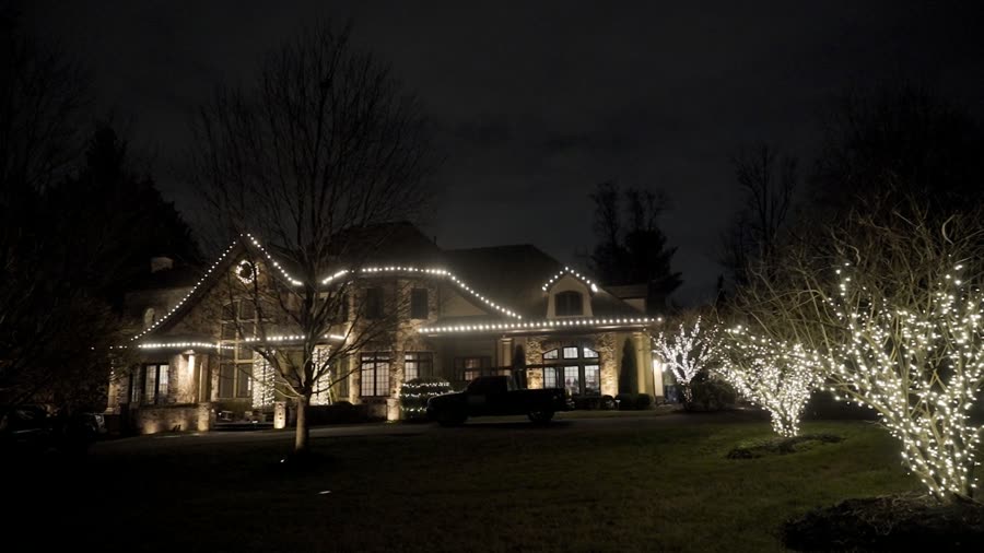Stone estate with roofline lighting and a wrapped tree